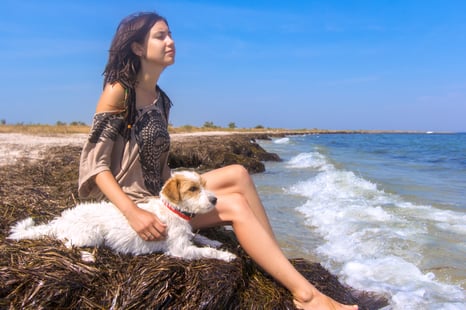 Young gal with her dog by the beach. 